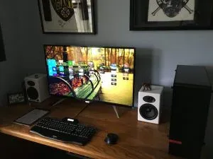 The finished desk, huge monitor mid-game with the white speakers either side and the black tower at right