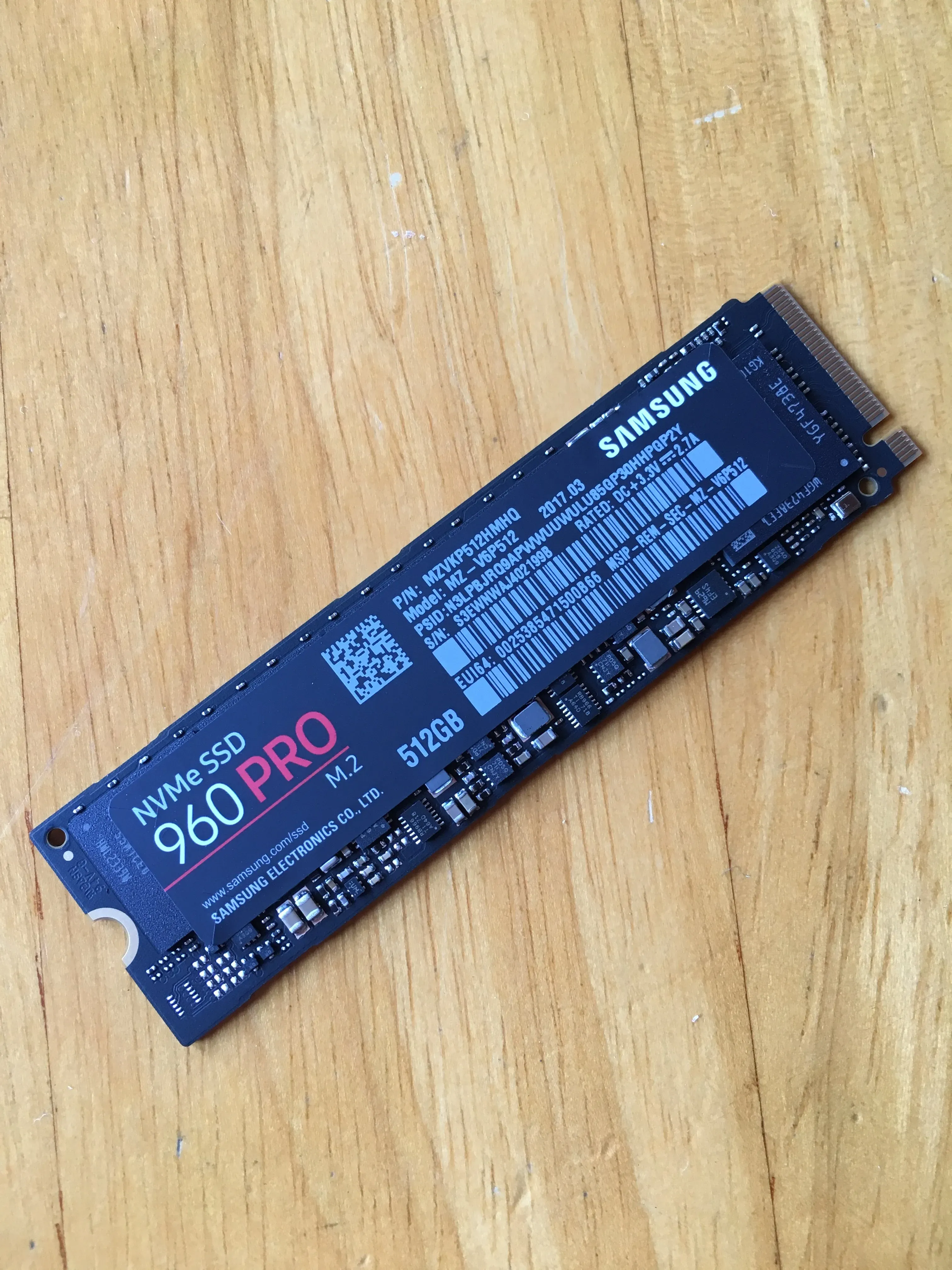 Bare blue circuit board of a Samsung 960 Pro NVMe M.2 drive, 512 GB, on a wooden table