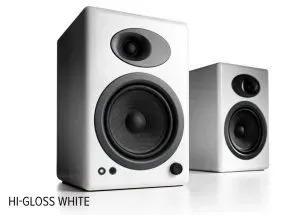 A matched pair of bookshelf speakers in gloss white, one set behind the other