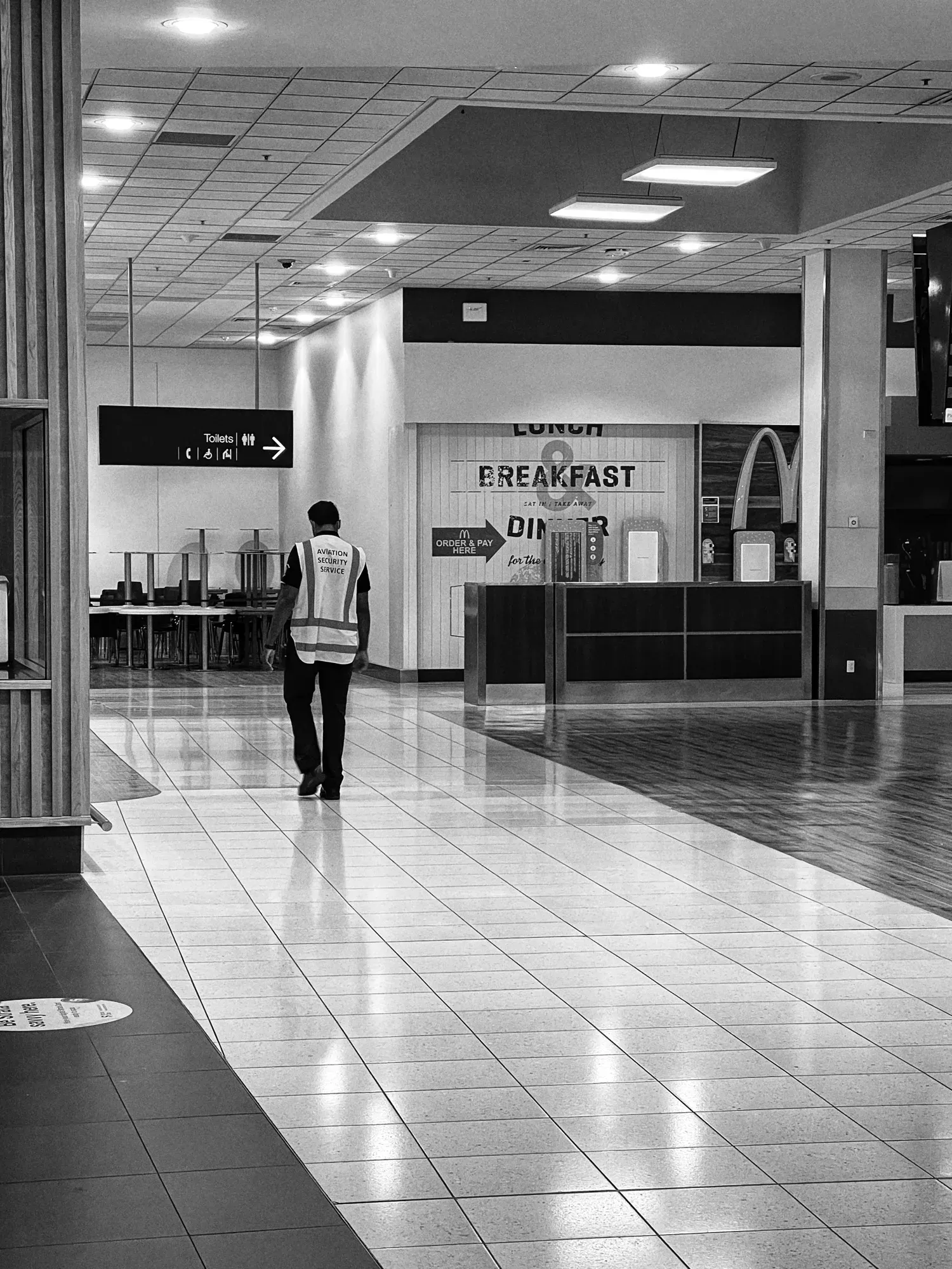 An Aviation Security officer walks alone past a shuttered McDonald's counter
