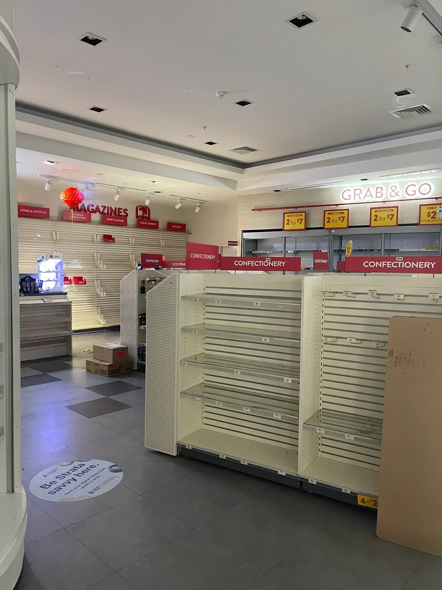 Stripped bare shelves under Confectionery and Grab & Go signs in a closed airport shop