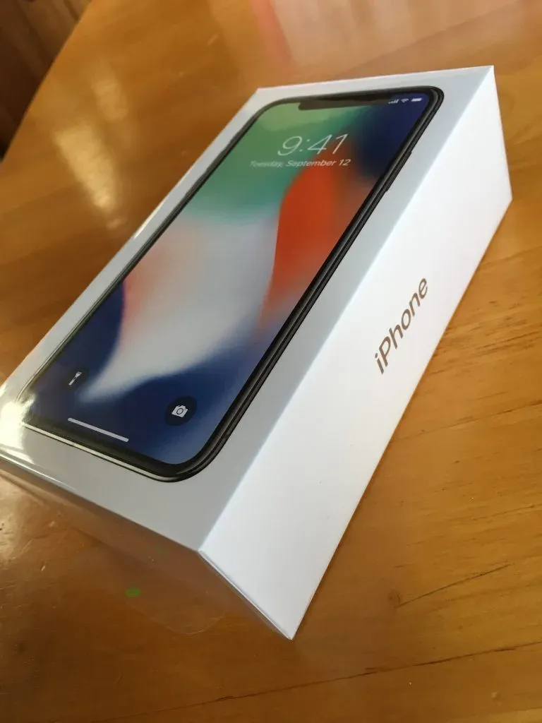 Sealed iPhone X box still in its plastic wrap, propped on a wooden table