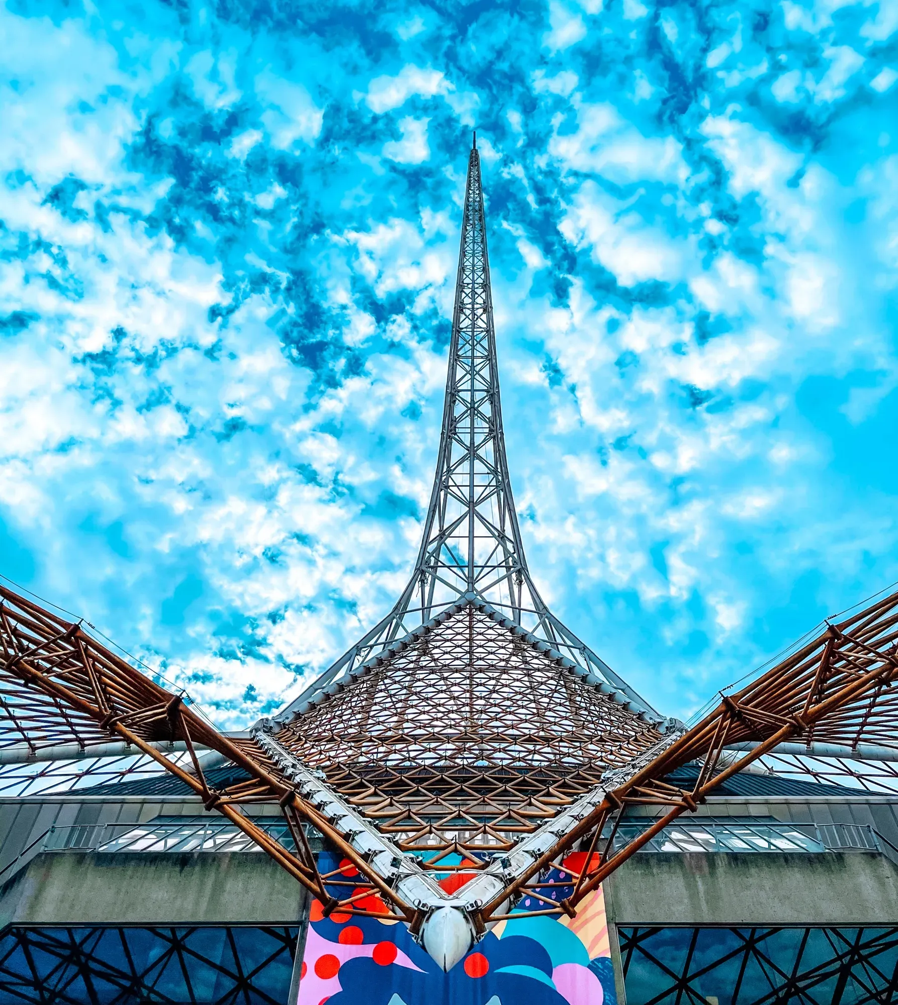 Looking straight up the Arts Centre spire through its lattice canopy into a mottled blue sky