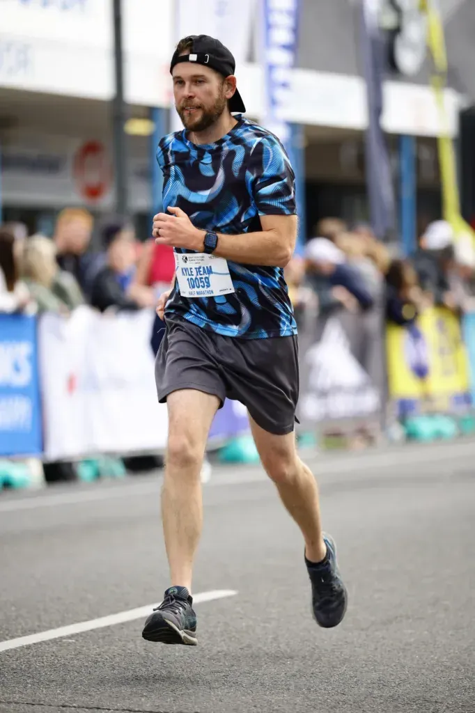 Kyle running the last stretch into Apollo Bay, cap on backwards, spectators and barriers blurred behind