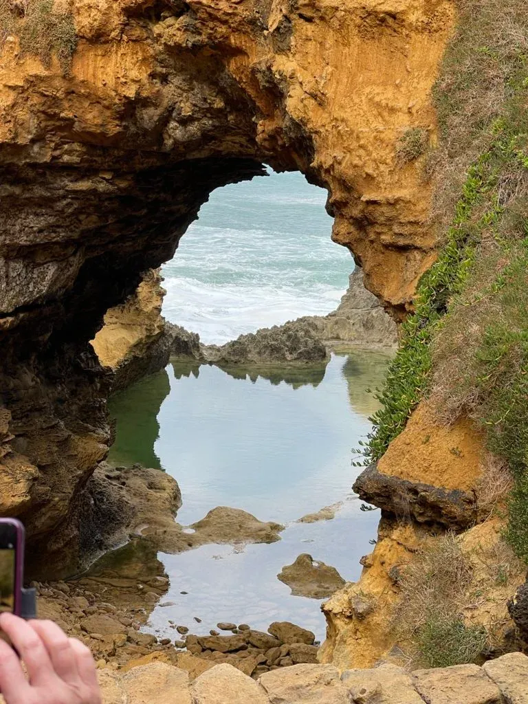 The arch doubled in the still pool below it, a phone screen held up at the edge of the frame