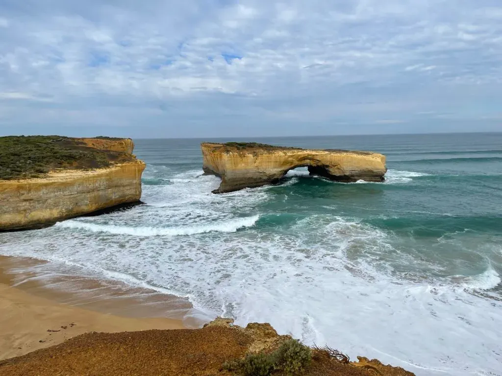 A flat-topped stack with an arch at its base, standing off a wide empty beach