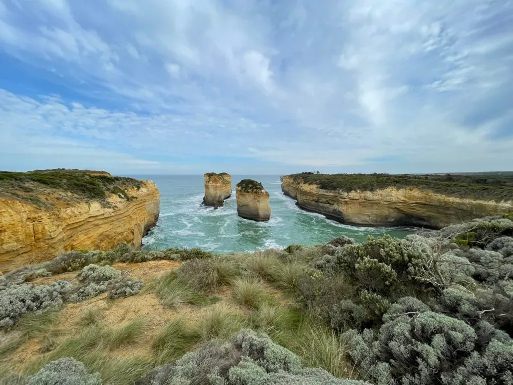 Two rock stacks standing in the inlet between scrub-topped cliffs