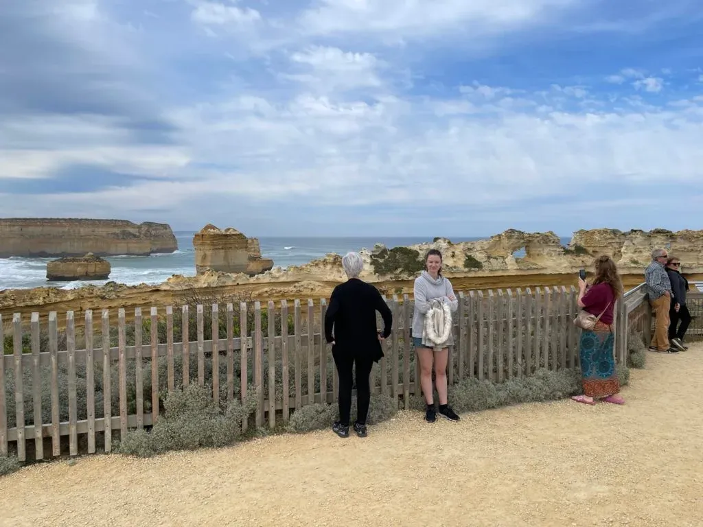 Visitors along a picket fence at the lookout, one posing for a photo with the stacks behind