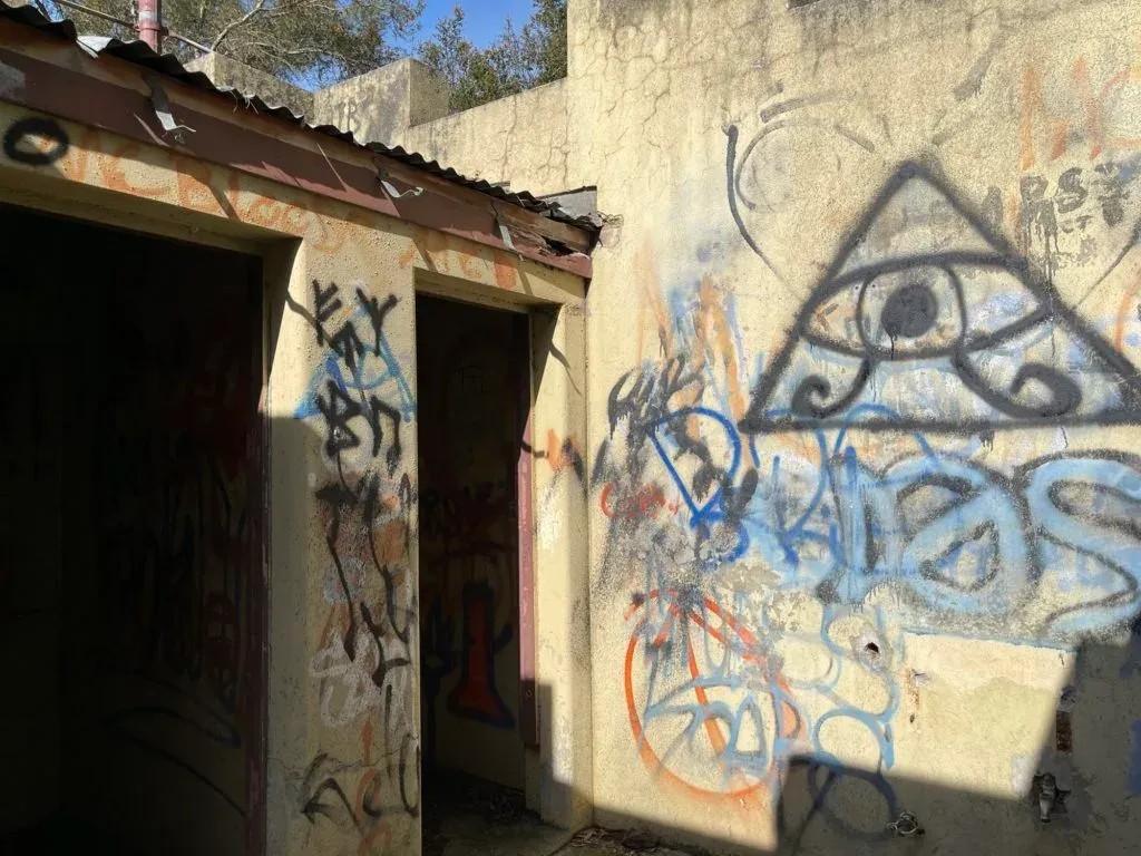 An abandoned block building covered in graffiti, an eye inside a triangle sprayed on the wall