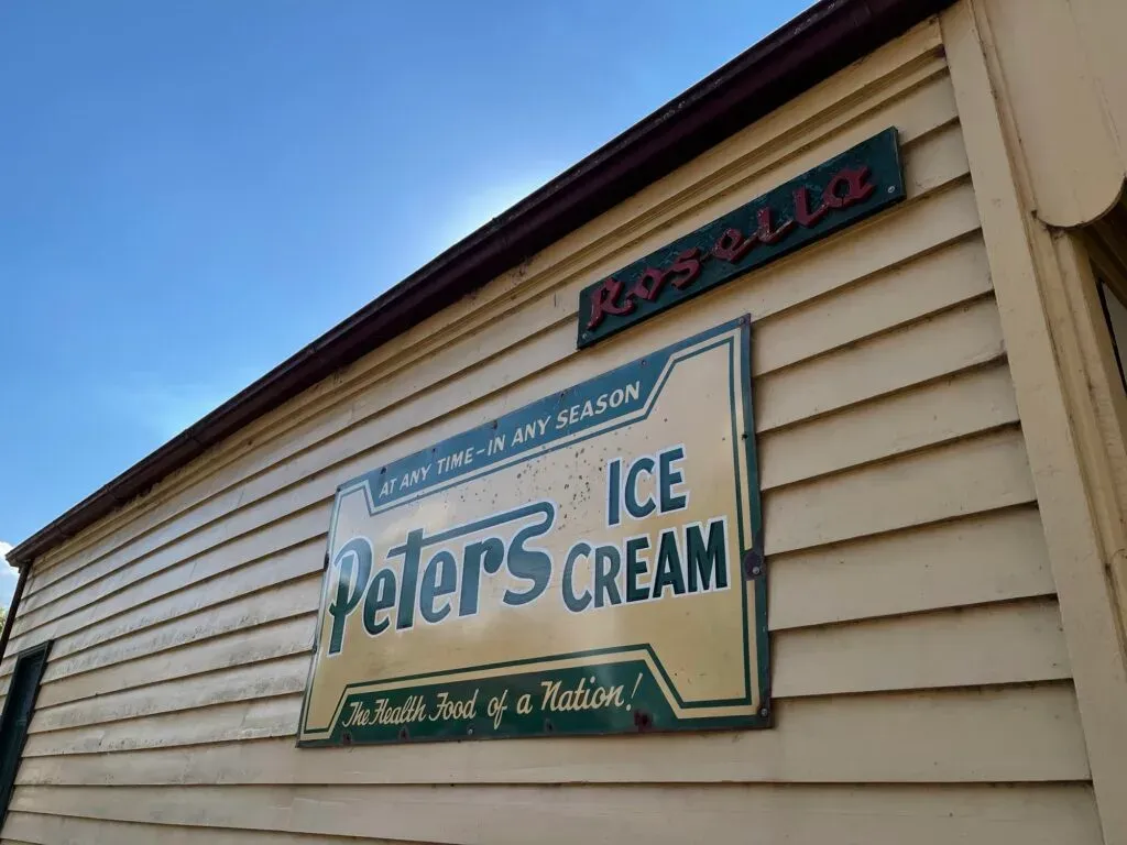 Enamel Peters Ice Cream sign on a weatherboard wall reading The Health Food of a Nation, a Rosella sign above