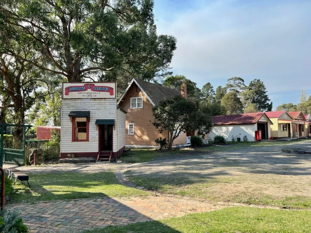 Tiny weatherboard office signed Barrister & Solicitor, a larger gabled house and sheds behind it