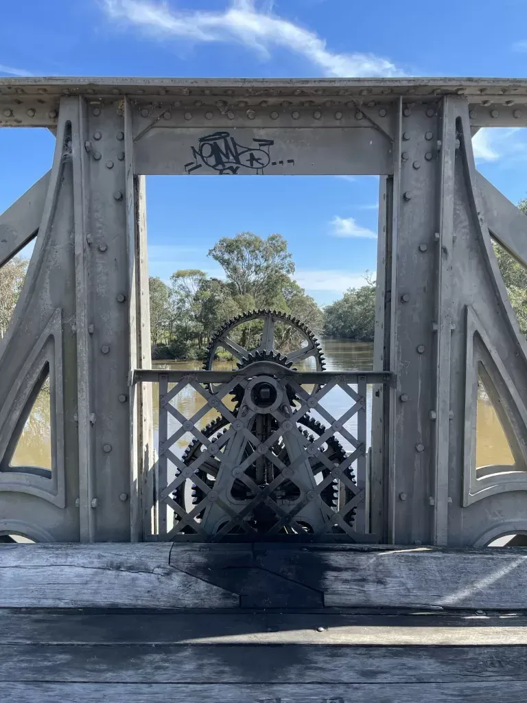 The bridge's exposed turning gears framed by the central portal, a tag sprayed on the crossbeam