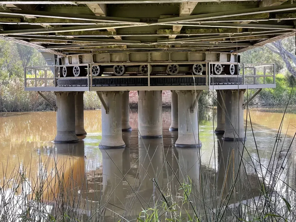 Looking up under the deck at the row of rollers and the piers standing in still water