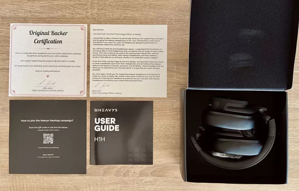 Box contents laid out: certificate, letter from Axel Grell, QR hashtag card, H1H user guide, and the folded headphones in their tray