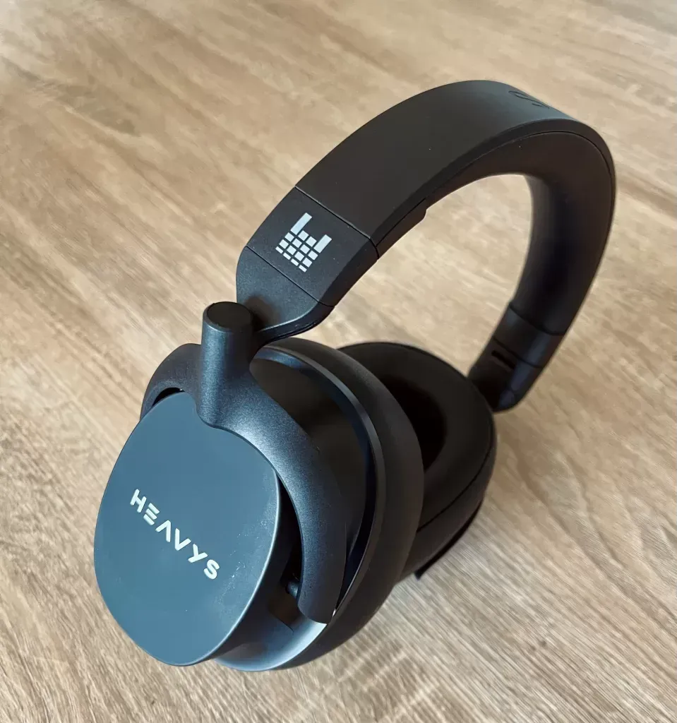 Headphones stood upright on one cup, Heavys wordmark on the outer plate and the grid logo on the band
