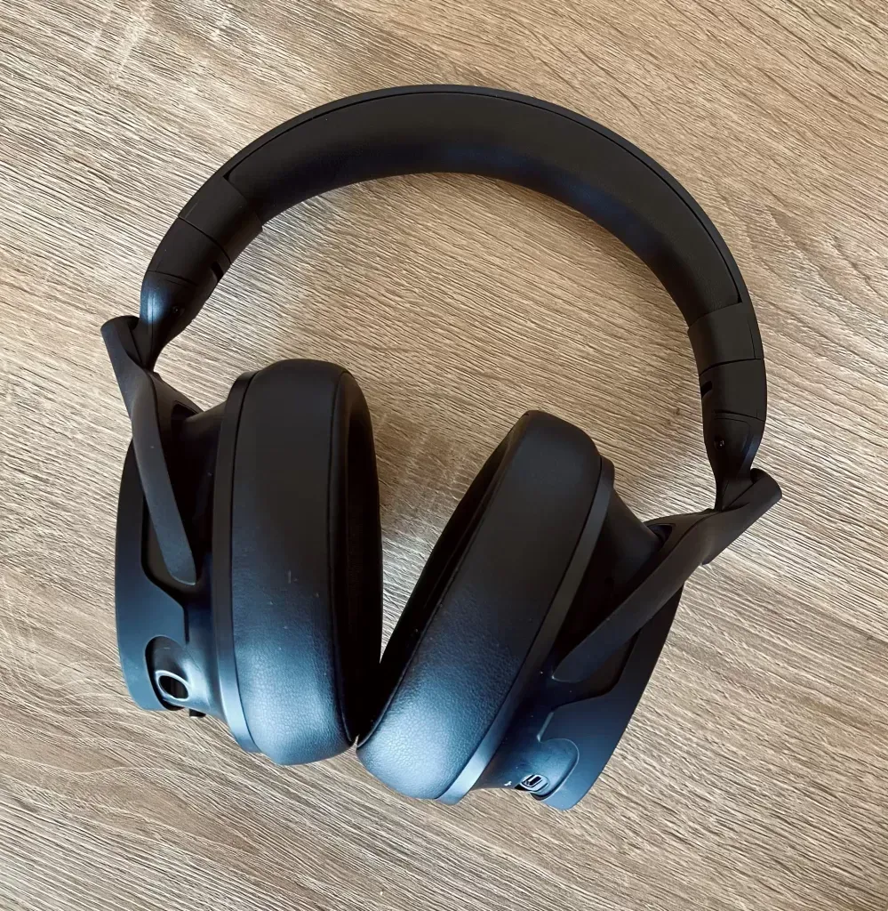 The black headphones lying flat, padded band arched above the two oversized leather earcups